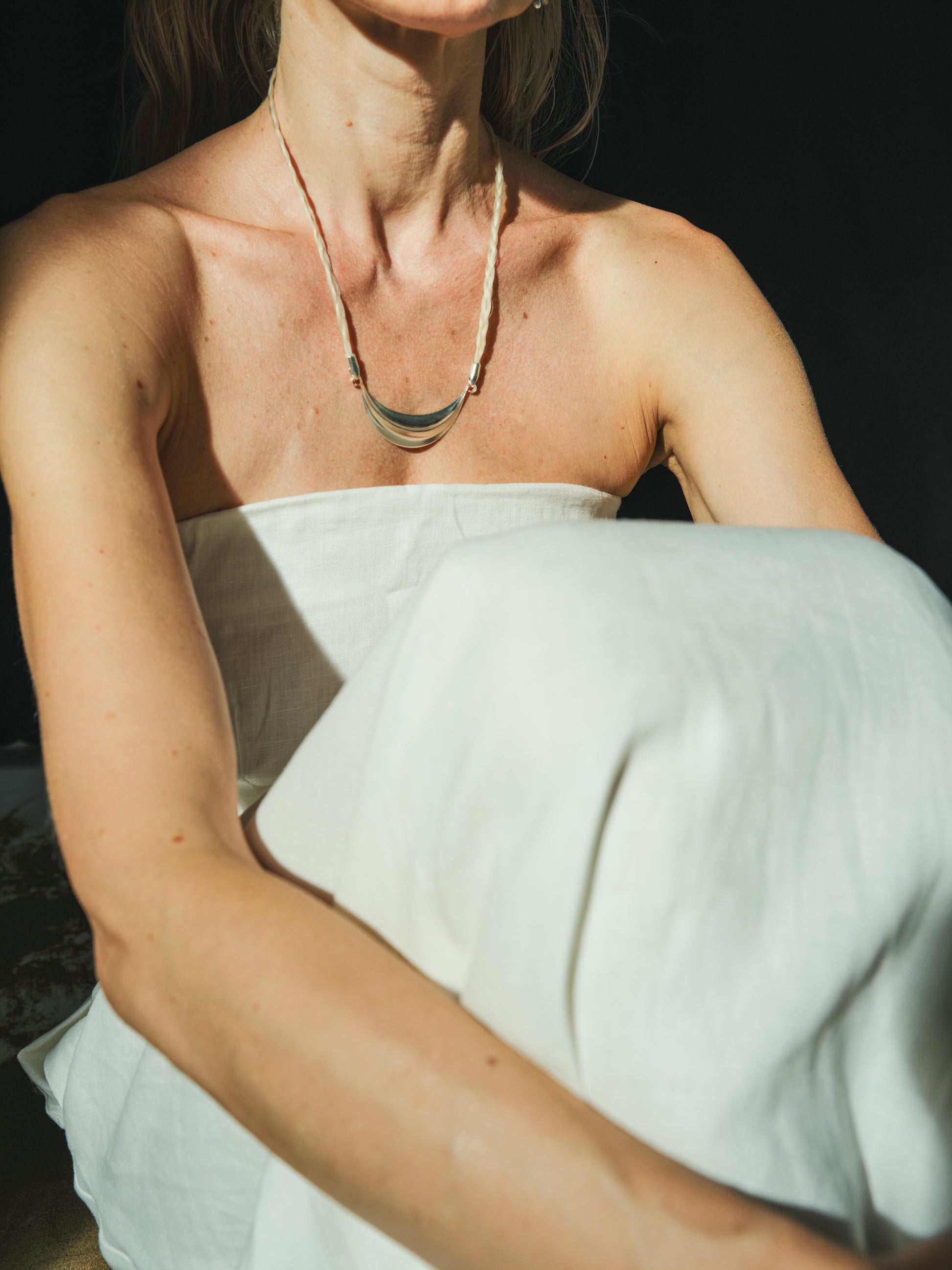 Silver crescent necklace by RIVERLAKE, featuring a delicate design and minimalist style on a soft fabric background.
