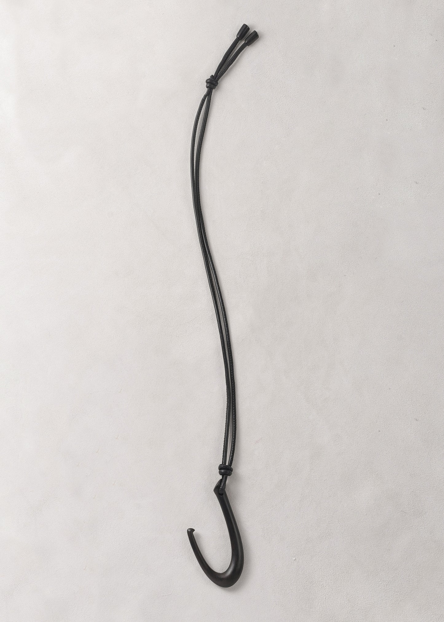 RIVERLAKE Hook Pendant in Ebony with a sleek, modern design and a polished finish hanging on a minimalist display.