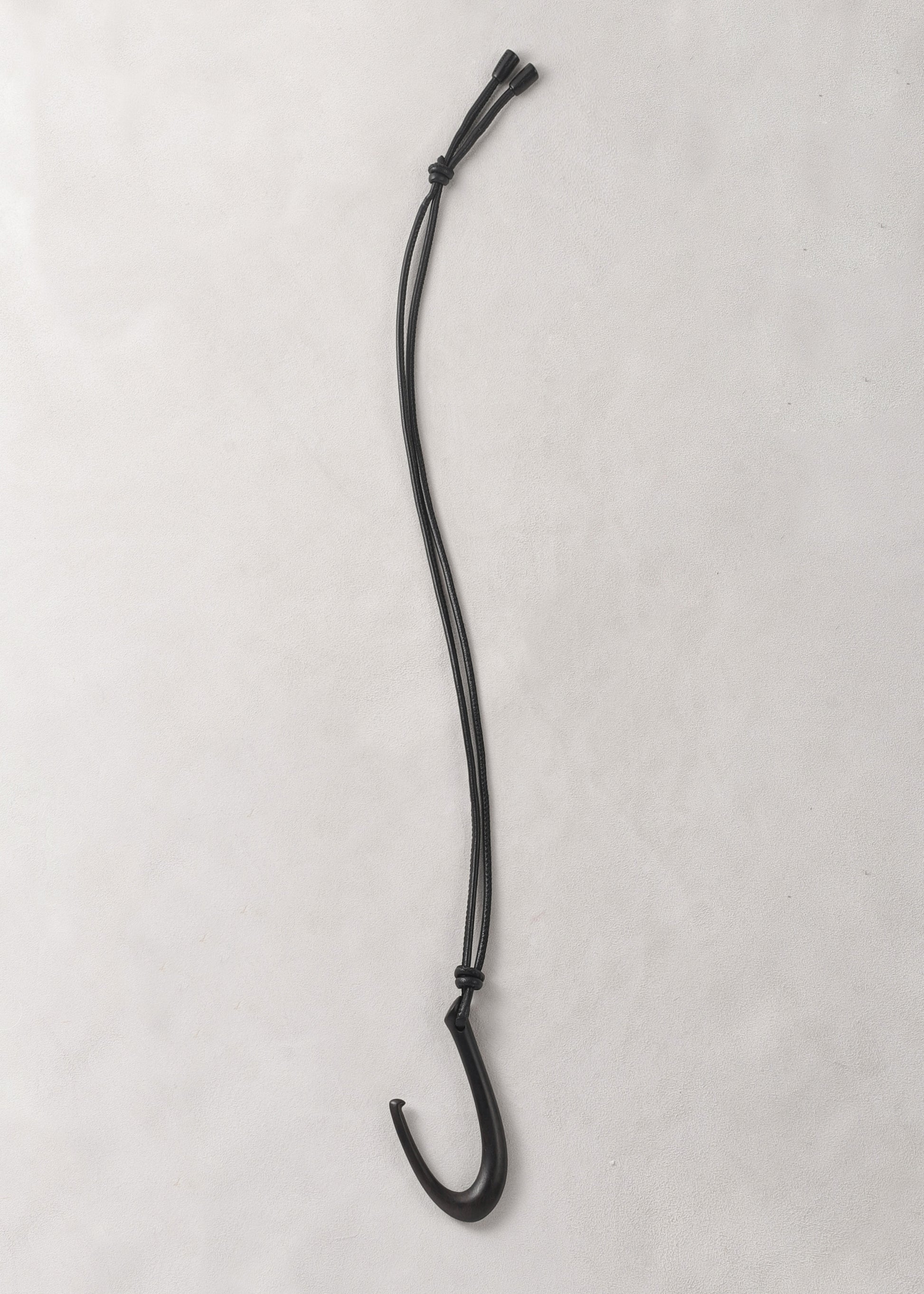 RIVERLAKE Hook Pendant in Ebony with a sleek, modern design and a polished finish hanging on a minimalist display.